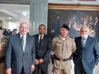 four men in suits standing next to a painting