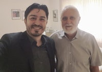 two men posing for a photo in a room